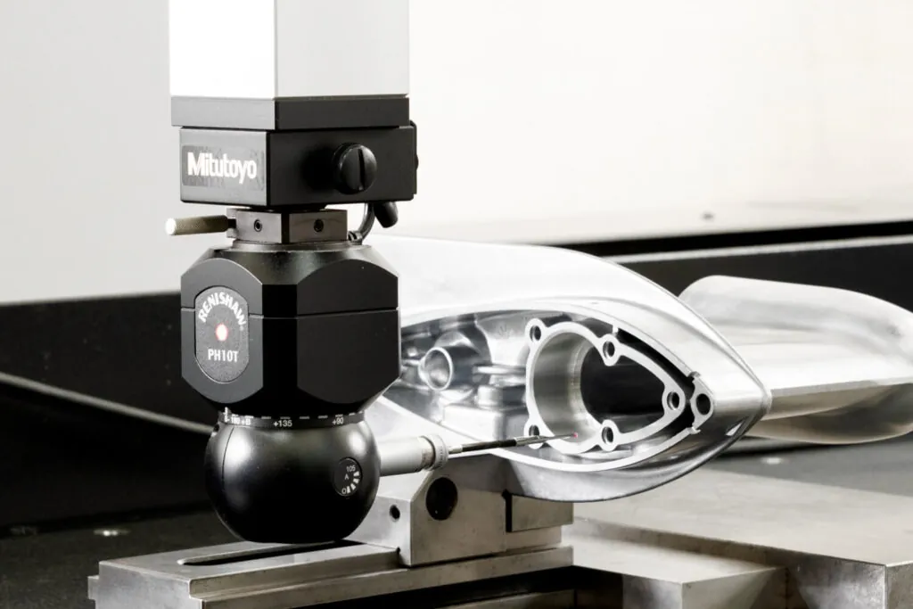 Mitutoyo CMM sampling and Renishaw PH10T probe performing automated dimensional verification on a precision aluminum die cast marine component.