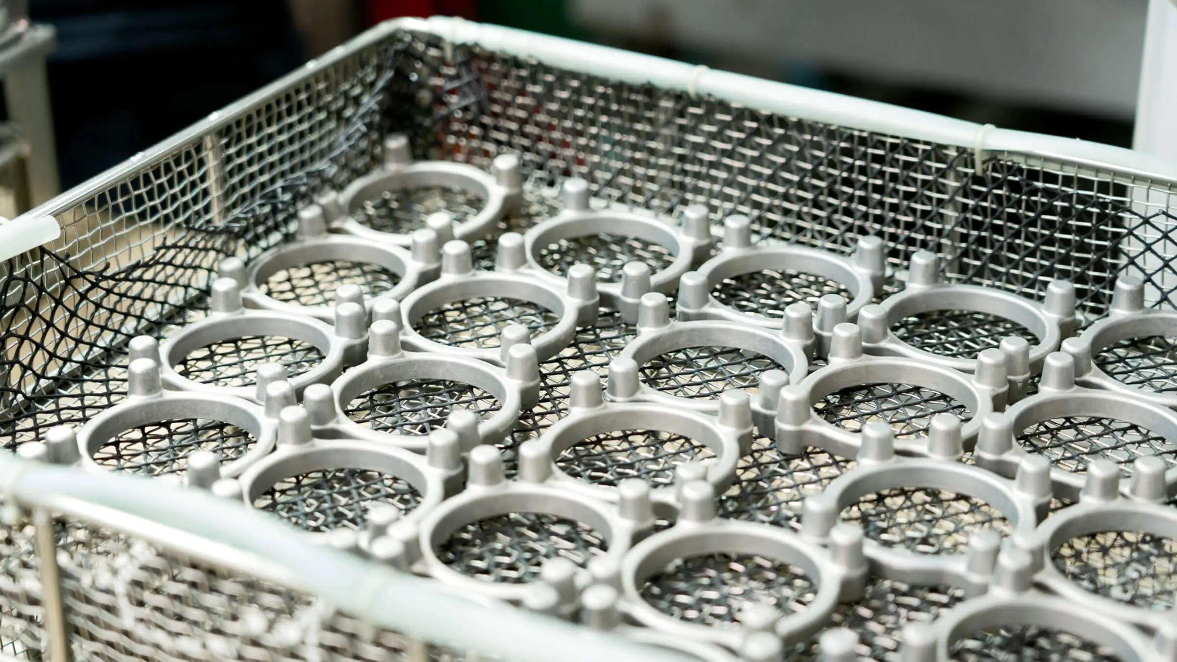 Aluminum die cast rings organized in stainless steel baskets for high-volume automated cleaning and surface preparation before final coating.