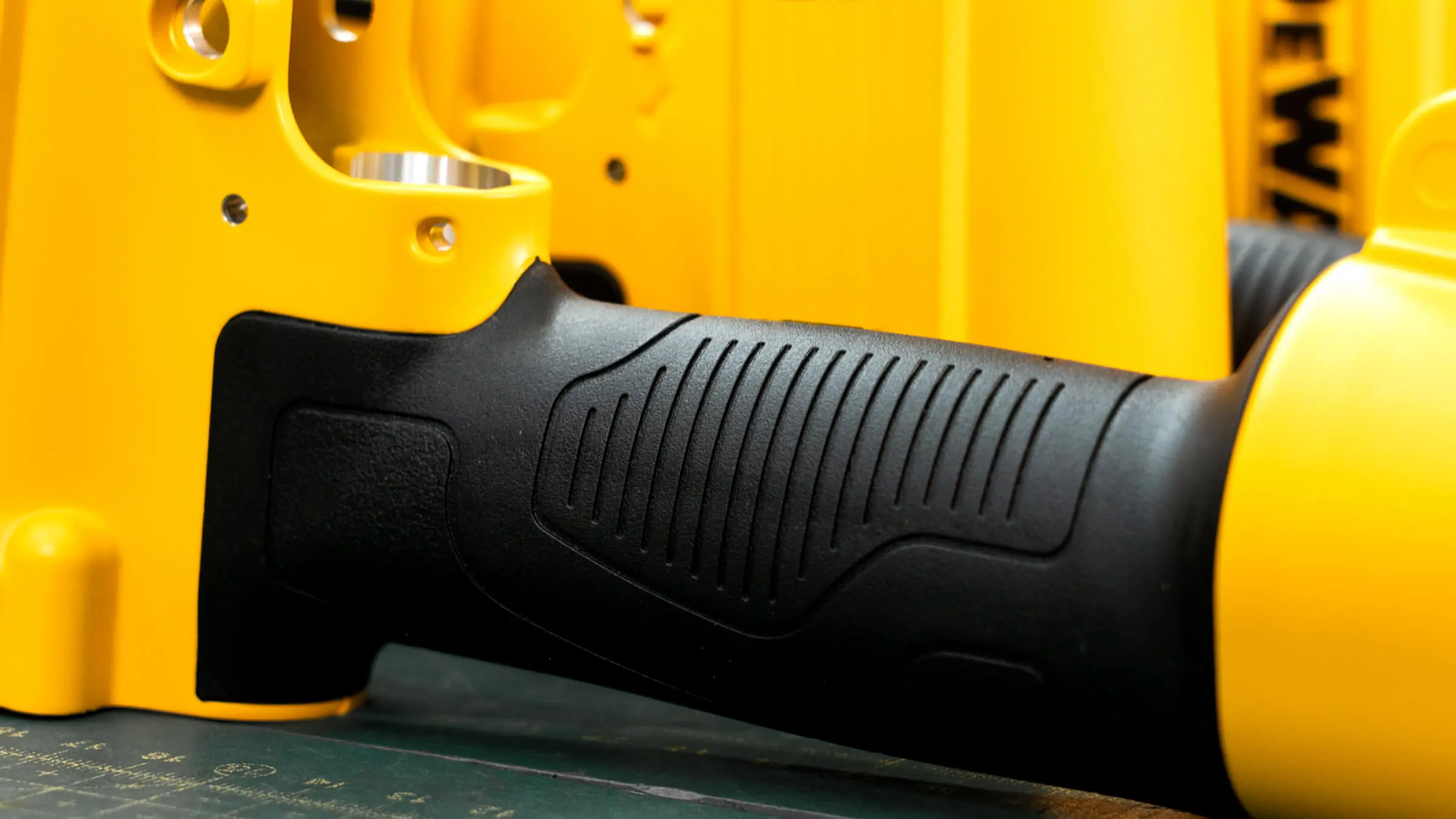 Ergonomic black TPR insert molding on a yellow aluminum die cast pneumatic tool housing, providing superior grip and vibration absorption.